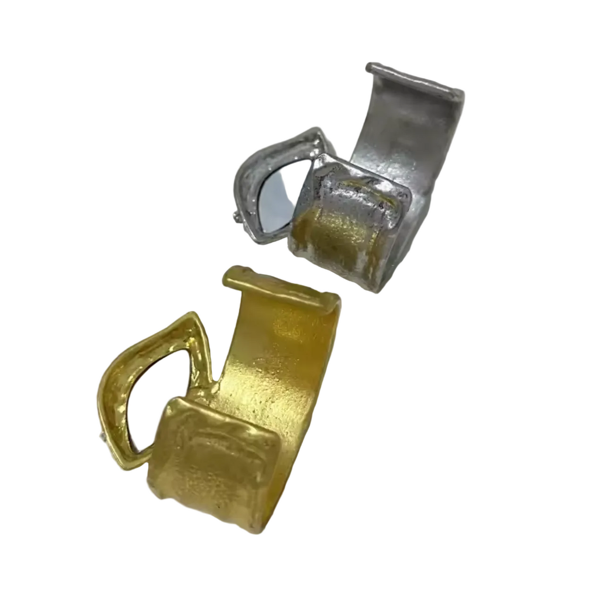 Two textured cuff-style rings with embedded oval mirrors, one in textured gold and one in textured silver, displayed on a plain off-white surface.