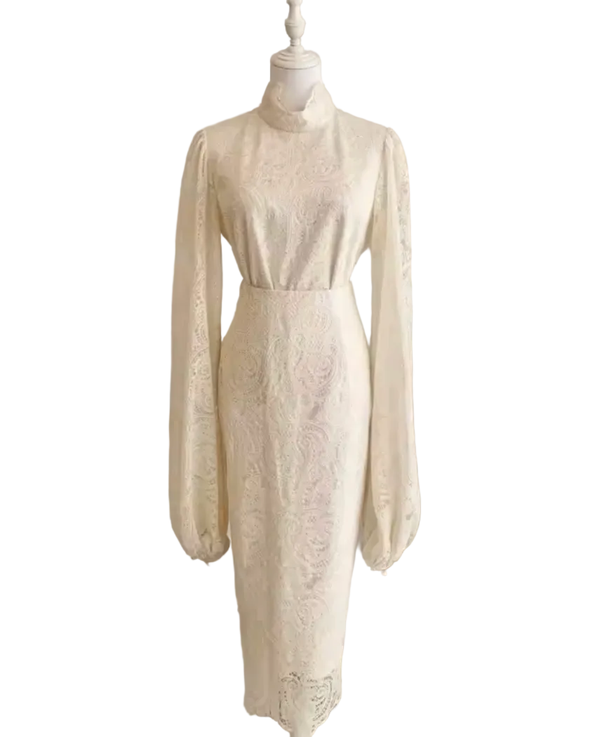 An ivory lace midi dress with long balloon sleeves and a high mock neck, displayed on a white mannequin in a softly lit indoor setting.