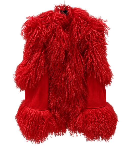 A vibrant red vest featuring a thick, curly shaggy faux fur collar and matching fringe trim at the hem, displayed on a hanger against a textured gray concrete wall.