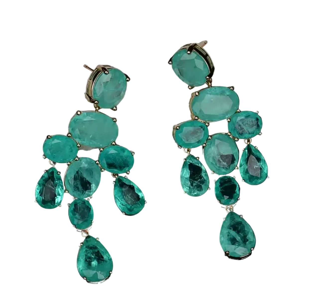 A pair of large drop earrings made of multiple faceted emerald-green gemstones in gold-tone settings, displayed against a white textured stone slab on a black background.