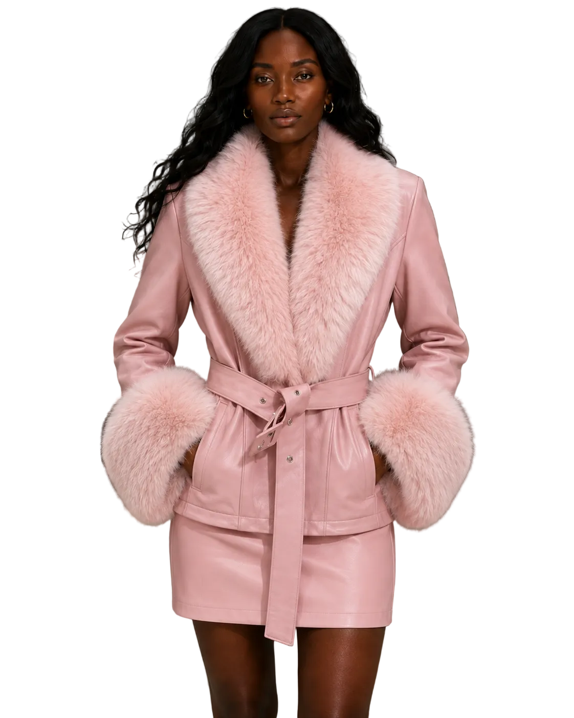 A model wearing a light pink faux-leather wrap coat with a large fluffy faux-fur collar and matching faux-fur cuffs, paired with a matching belt and mini skirt, set against a textured gray concrete wall.