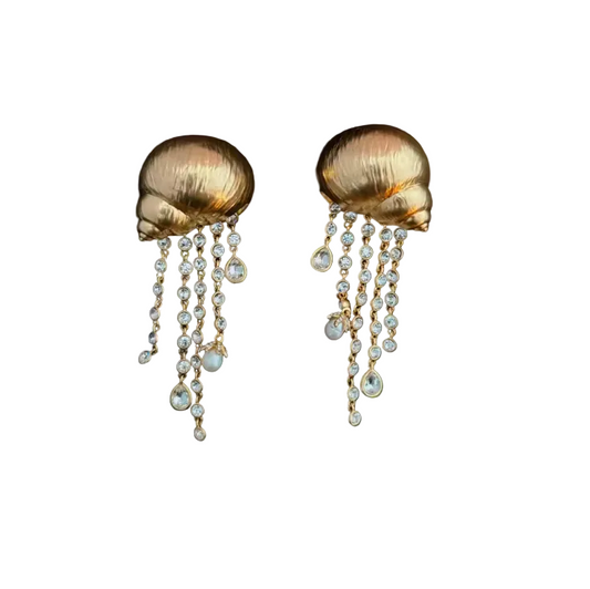 A pair of gold-toned shell-shaped drop earrings with dangling pearl-like beads, shown on a black background.