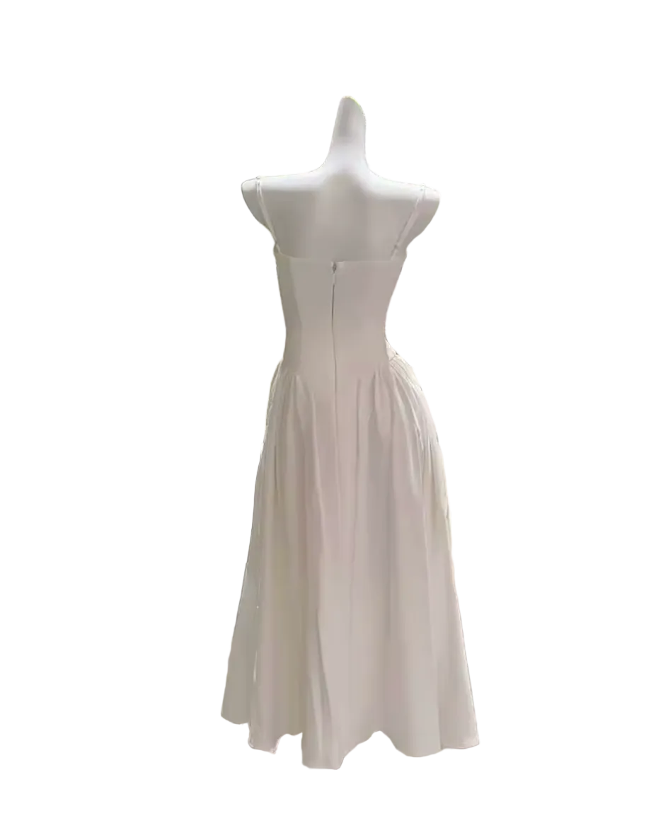 A white sleeveless midi dress displayed on a white mannequin torso in an indoor showroom. The dress has a structured, slightly gathered bodice and a flowing skirt.
