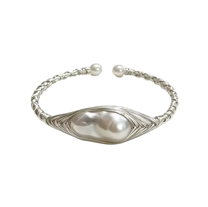 A silver-toned open cuff bracelet featuring a large baroque pearl in the center, surrounded by a textured leaf-like wire frame, with a twisted rope-style band and small pearl end caps, photographed on a white background with soft shadows.
