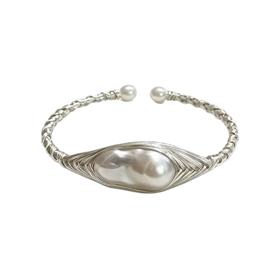 A silver-toned open cuff bracelet featuring a large baroque pearl in the center, surrounded by a textured leaf-like wire frame, with a twisted rope-style band and small pearl end caps, photographed on a white background with soft shadows.